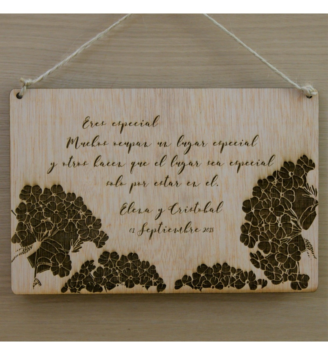 Placa de madera grabada con flores y texto personalizado.